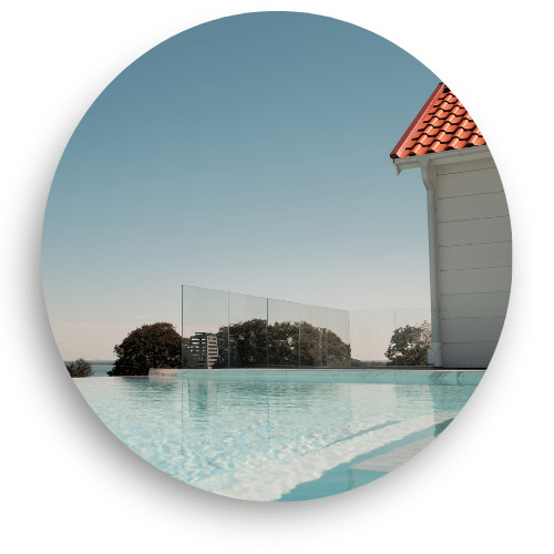 Stilrent glashegn uden stolper omkring pool, giver uafbrudt udsigt og elegant afgrænsning mod landskab og horisont.