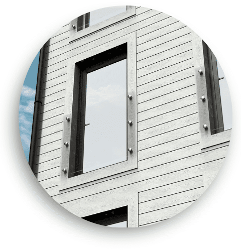 Fransk altan med glas og rustfrit stål foran fuldglasdøre på moderne træfacade – ideel til lejlighedskompleks.