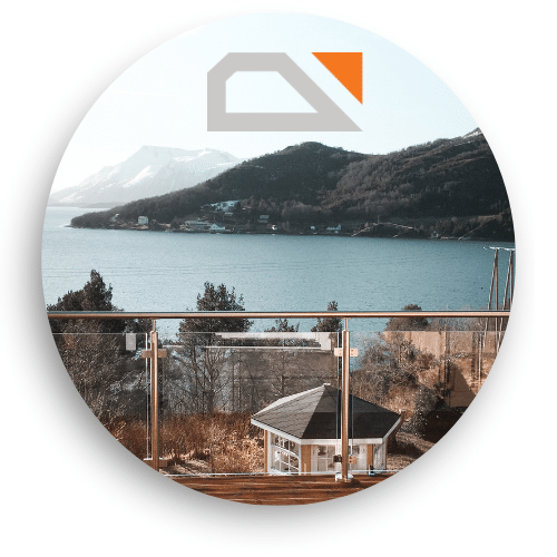 Glasgelænder med rustfri stolper og håndliste monteret på terrasse med panoramaudsigt over fjord, fjelde og hyggelige huse.