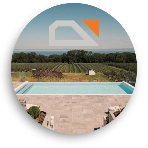 Glashegn med uafbrudt udsigt over marker og hav fra moderne terrasse ved infinitypool.