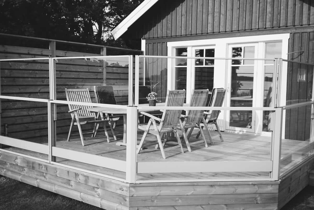 Hæve-sænke gelænder i glas og aluminium rundt om terrasse med havemøbler – praktisk og elegant løsning til udsigt og læ