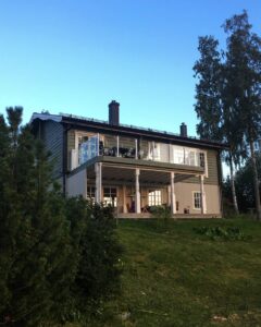 Glasgelænder i aluminium på altan i to plan med søjler og loungeområde under terrassen.