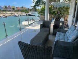 Glasværn med rustfrie stolper på terrasse med udsigt over bådkanal og farverige huse – perfekt glashegn til terrasse.