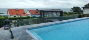 Glashegn ved pool med havudsigt Moderne glashegn omkring poolområde med havudsigt, elegant løsning der beskytter uden at forstyrre omgivelserne.